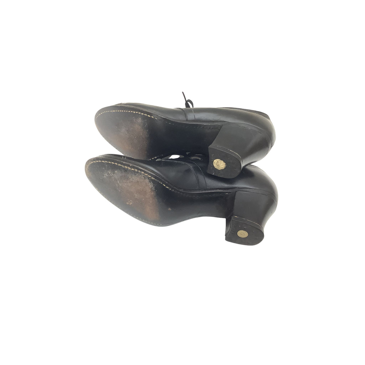 A pair of black leather mid-heeled shoes shown from the sole view, featuring a block heel.