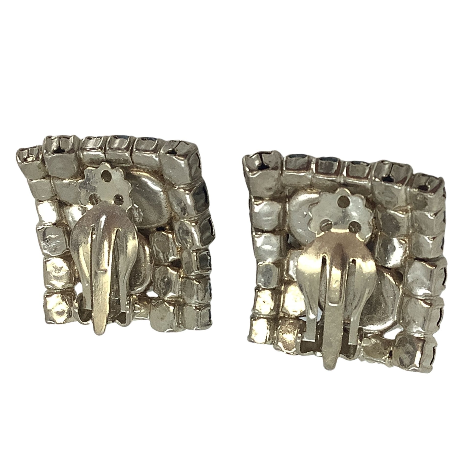 Back view of earrings with silver-tone design on a white background