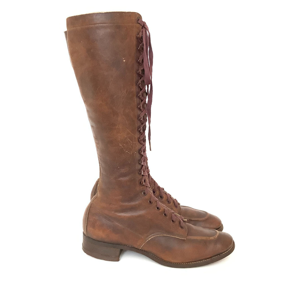Side view of a pair of antique lace-up women's boots in brown leather with a flat heel.