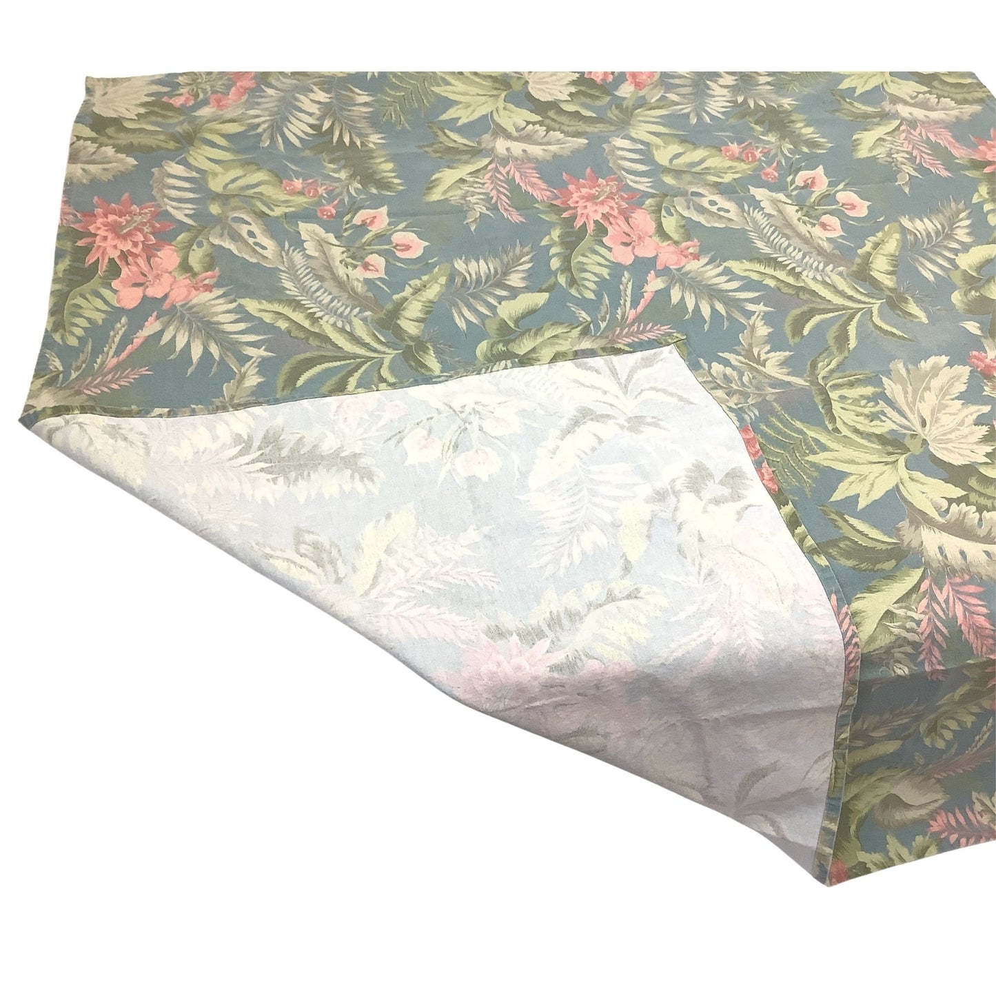 A square fabric tablecloth with a tropical floral and leaf pattern in muted green, pink, blue and white tones, shown with one corner folded over to reveal the white reverse side.