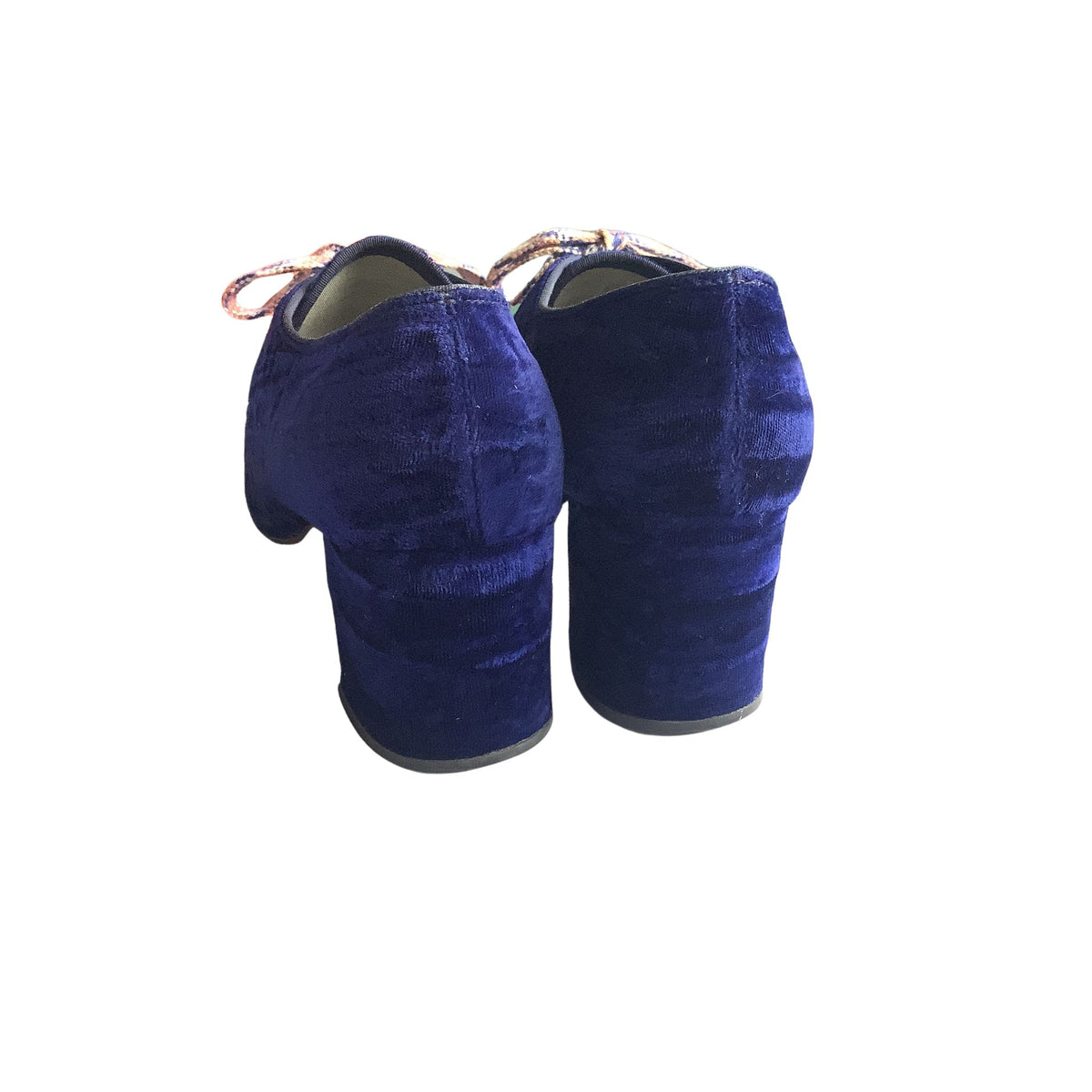 Back view of a pair of navy blue velvet shoes on a white background