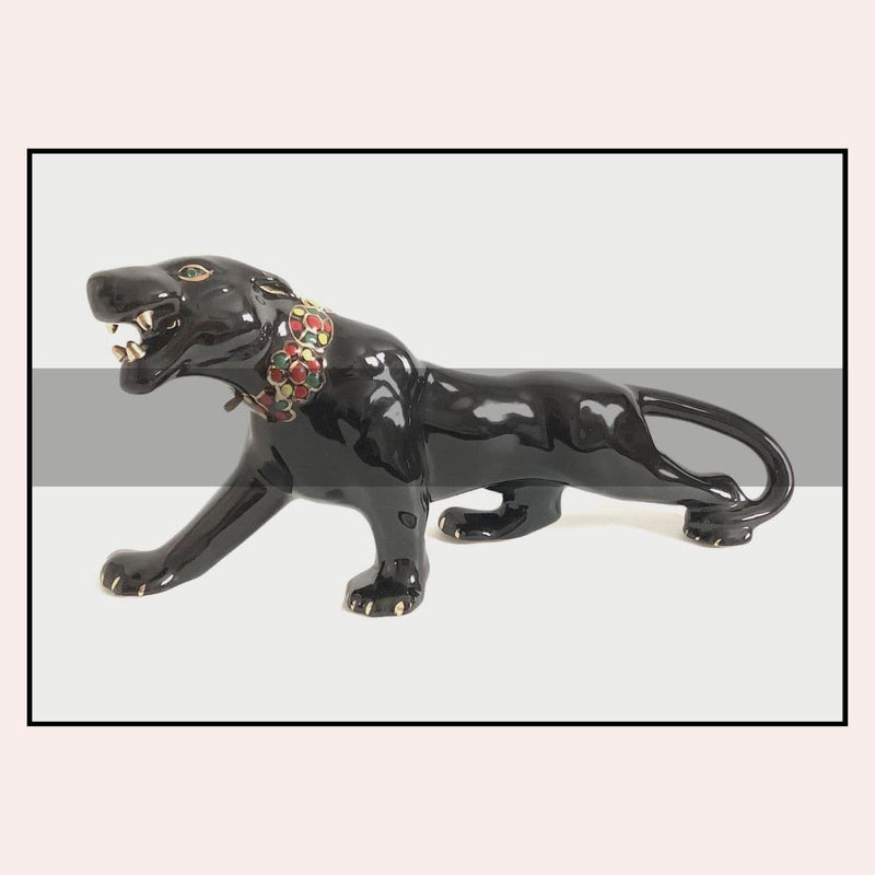 Black panther figurine with a decorative collar on a light gray background