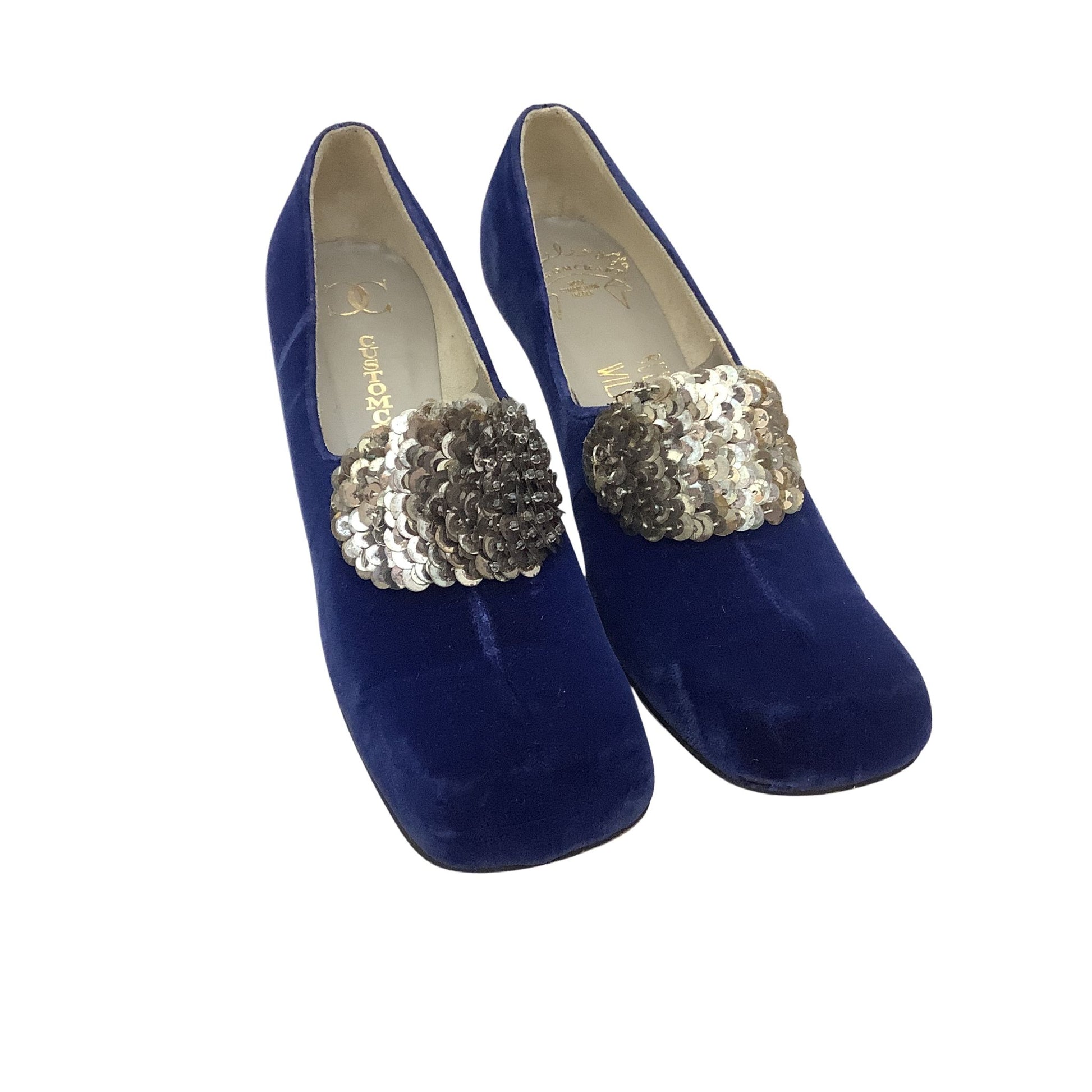 A pair of Custom Craft royal blue velvet pump shoes with a large silver sequin embellishment across the vamp, shown on a plain white background.