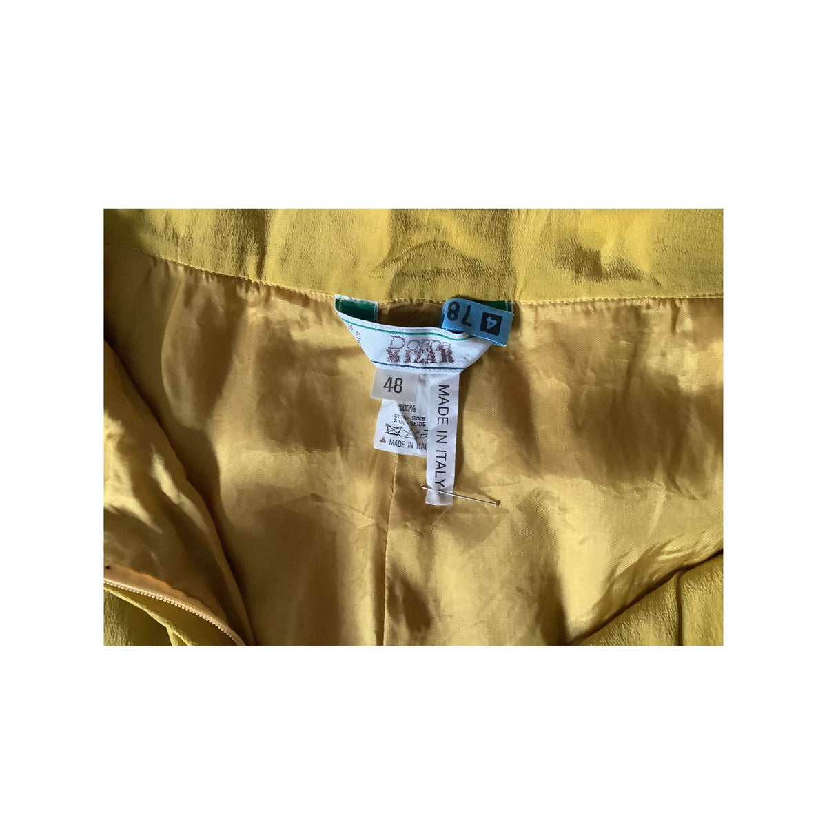 Close-up of interior waist area of pants showing a chartreuse green satin-like lining, brand, size and origin tag.