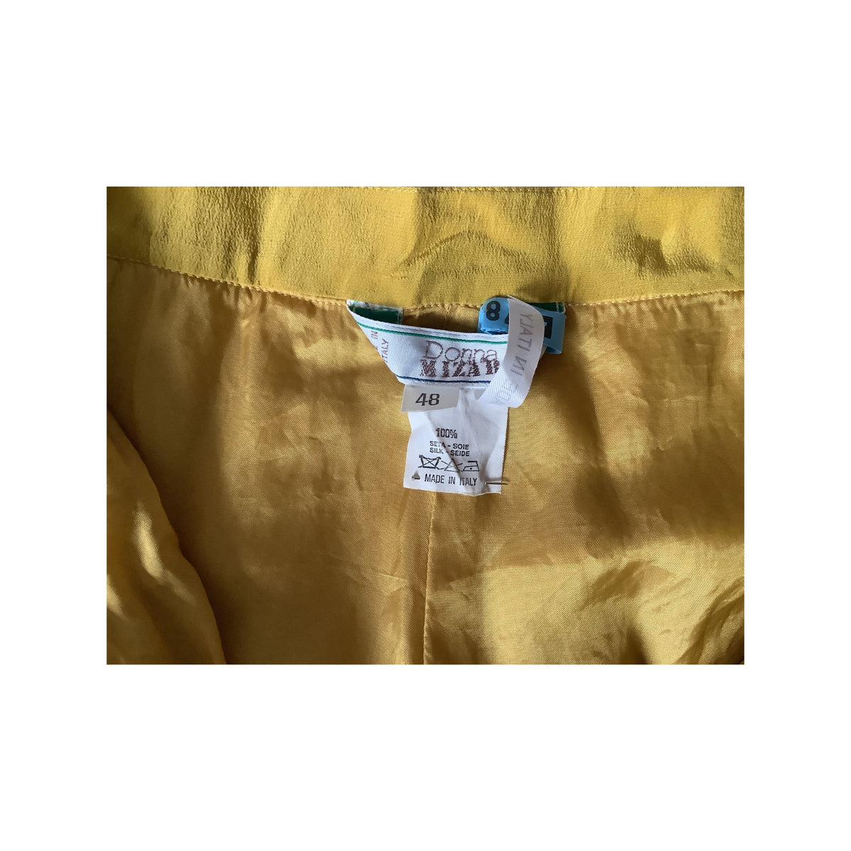 Close-up of a chartreuse garment interior showing material, size tag with the brand name Donna Mizar.