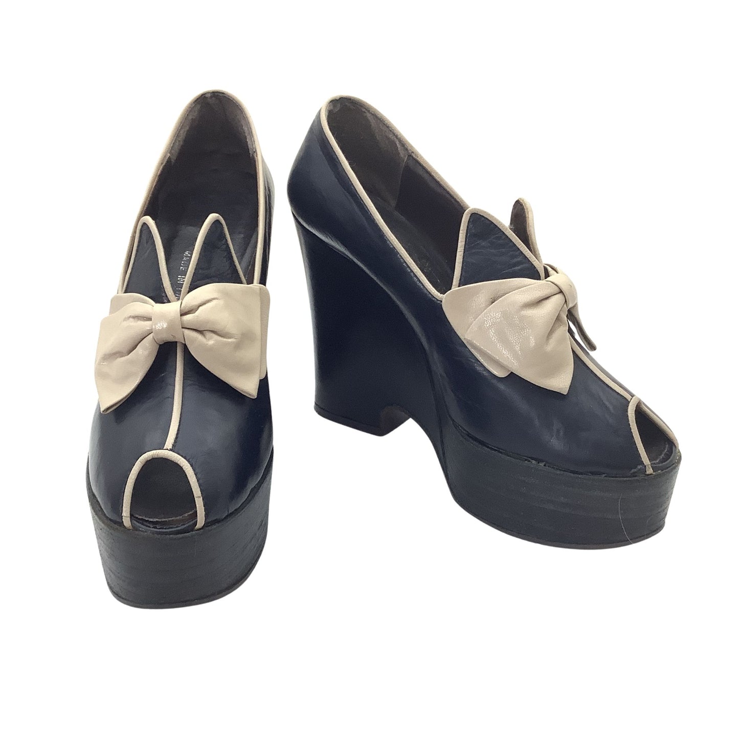 Vintage 1970s Elditas platform wedge pumps in navy blue leather with beige bow details and contrast piping, front and side view.
