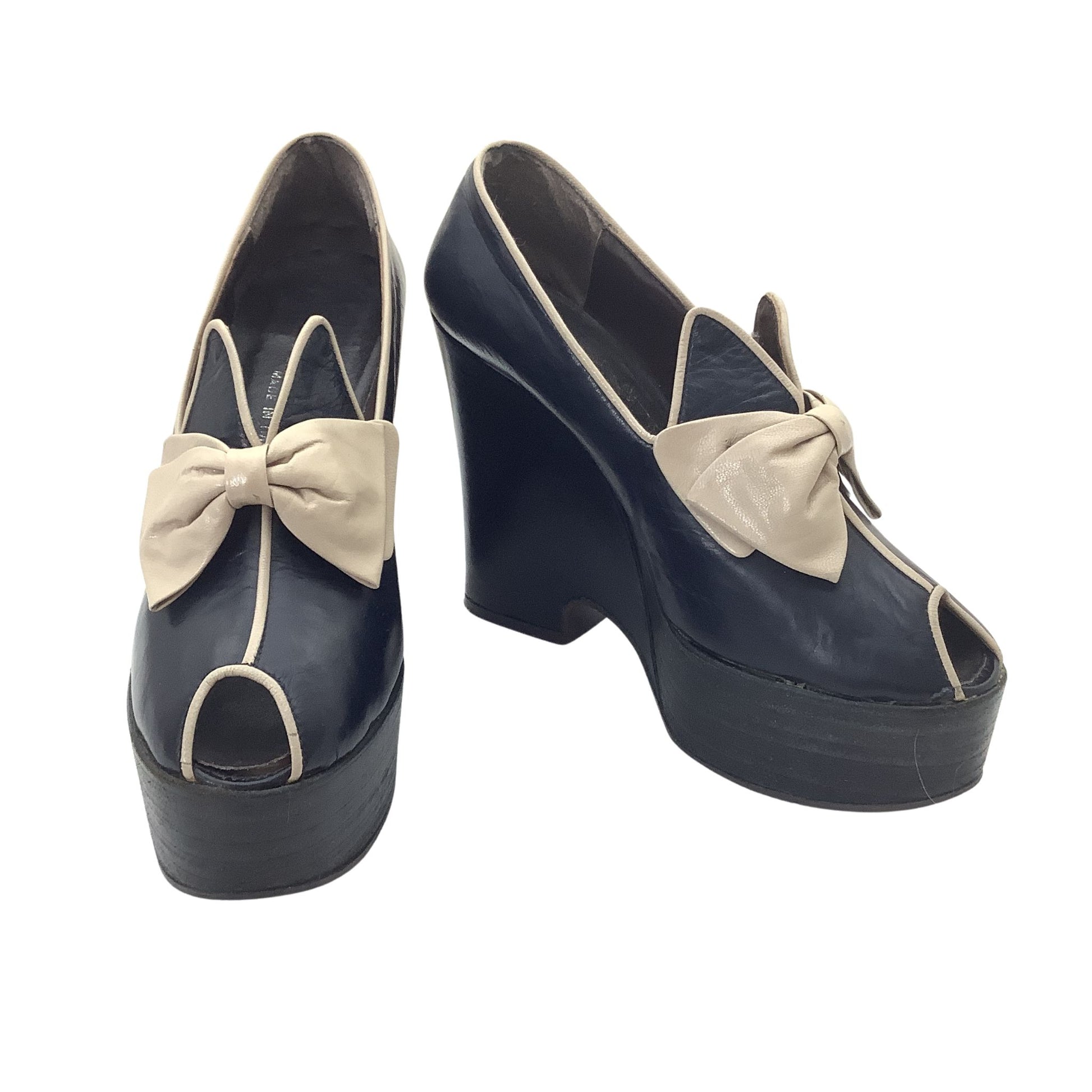Vintage 1970s Elditas platform wedge pumps in navy blue leather with beige bow details and contrast piping, front and side view.