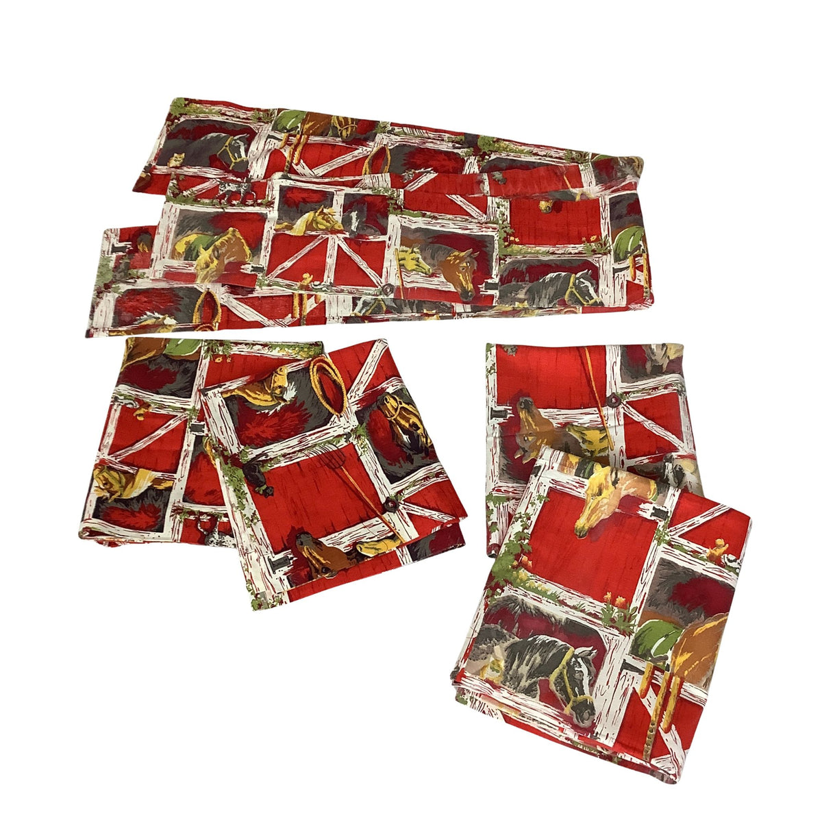 Four folded vintage western curtains and valance  with a rustic barn window print featuring red barn walls, white wooden frames, and illustrations of horses and a cowboy, displayed on a solid white background.