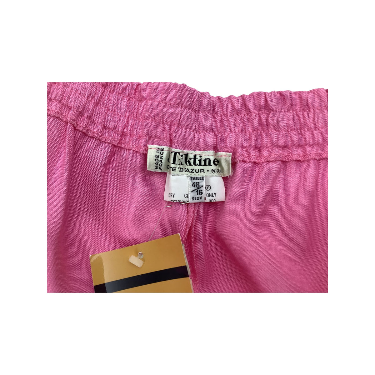 Close-up of the waistband and interior label of pink  pants waistband with 'Tiktiner' label.