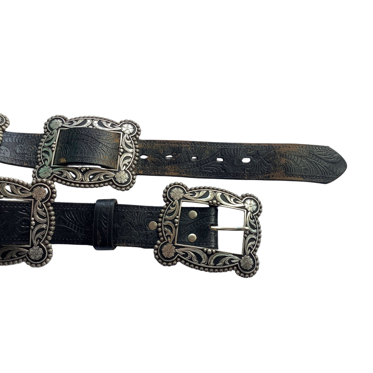Nocona black tooled leather belt with ornate silver-tone western-style buckle and square shaped Conchos, shown laid out on a plain white background.