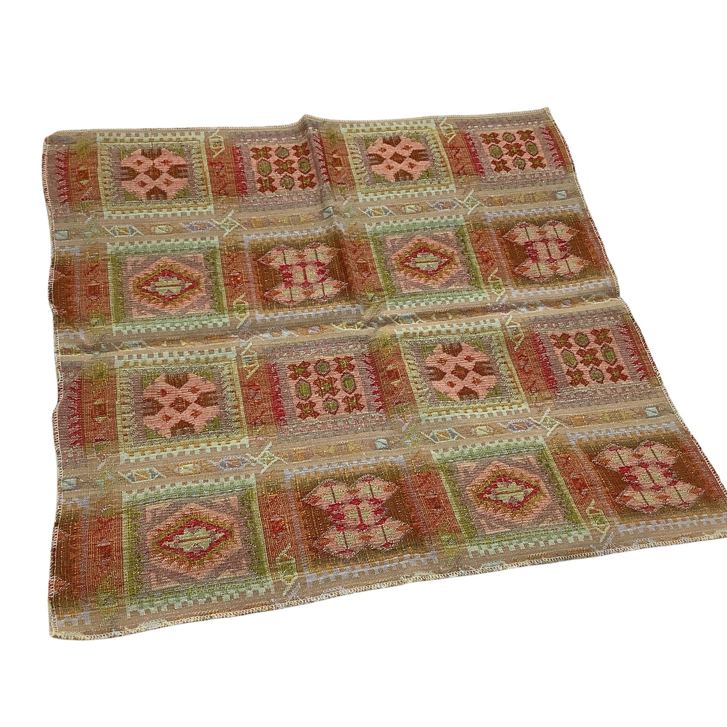Back view of a vintage kilim-style fabric sample featuring a geometric patchwork pattern in muted shades of terracotta, sage green, beige, and brown on a white background.