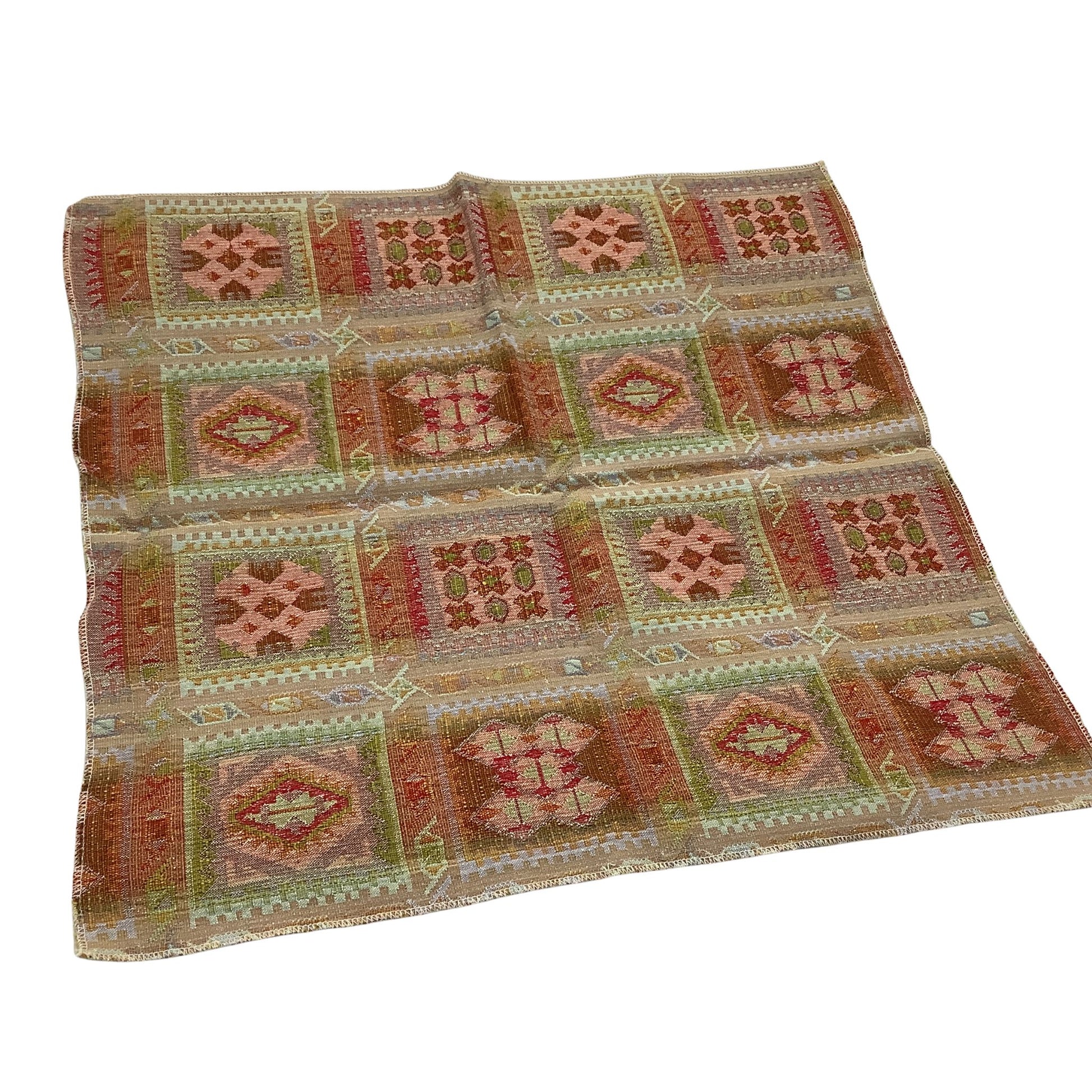 Back view of a vintage kilim-style fabric sample featuring a geometric patchwork pattern in muted shades of terracotta, sage green, beige, and brown on a white background.