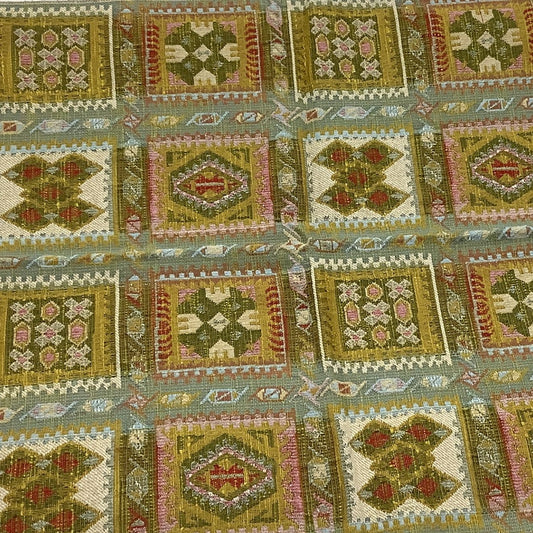 front view of a vintage fabric sample in a geometric patchwork pattern in olive green, beige, pink, and red.