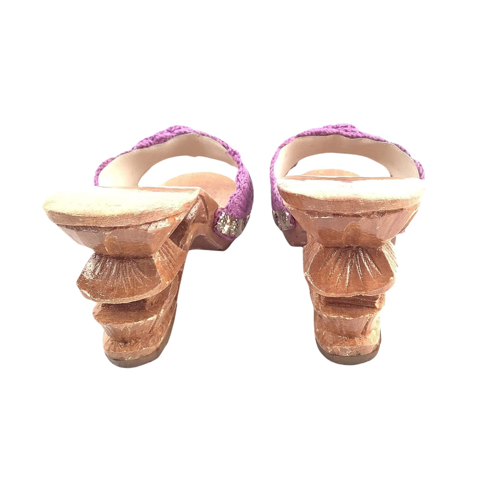 Back view of pair of sandals with purple straps on a white background