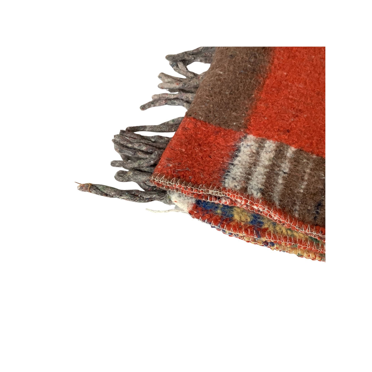 A close-up detail of a woven throw blanket showing its fringe, patterned design with rust red, brown, and cream stripes, and a multicolored border.