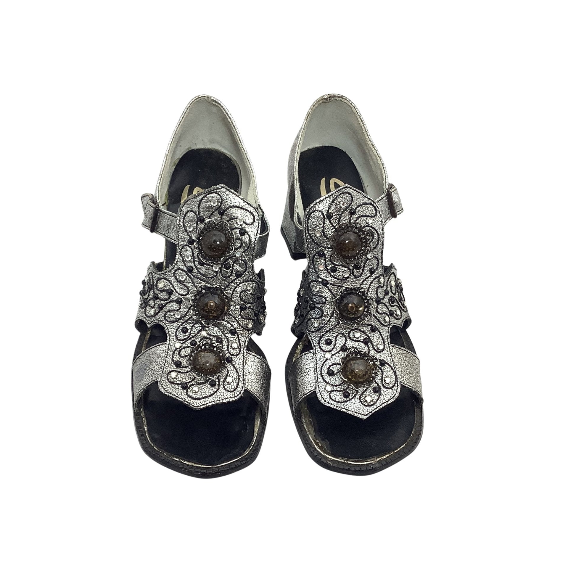 Pair of silver sandals with decorative straps on a white background