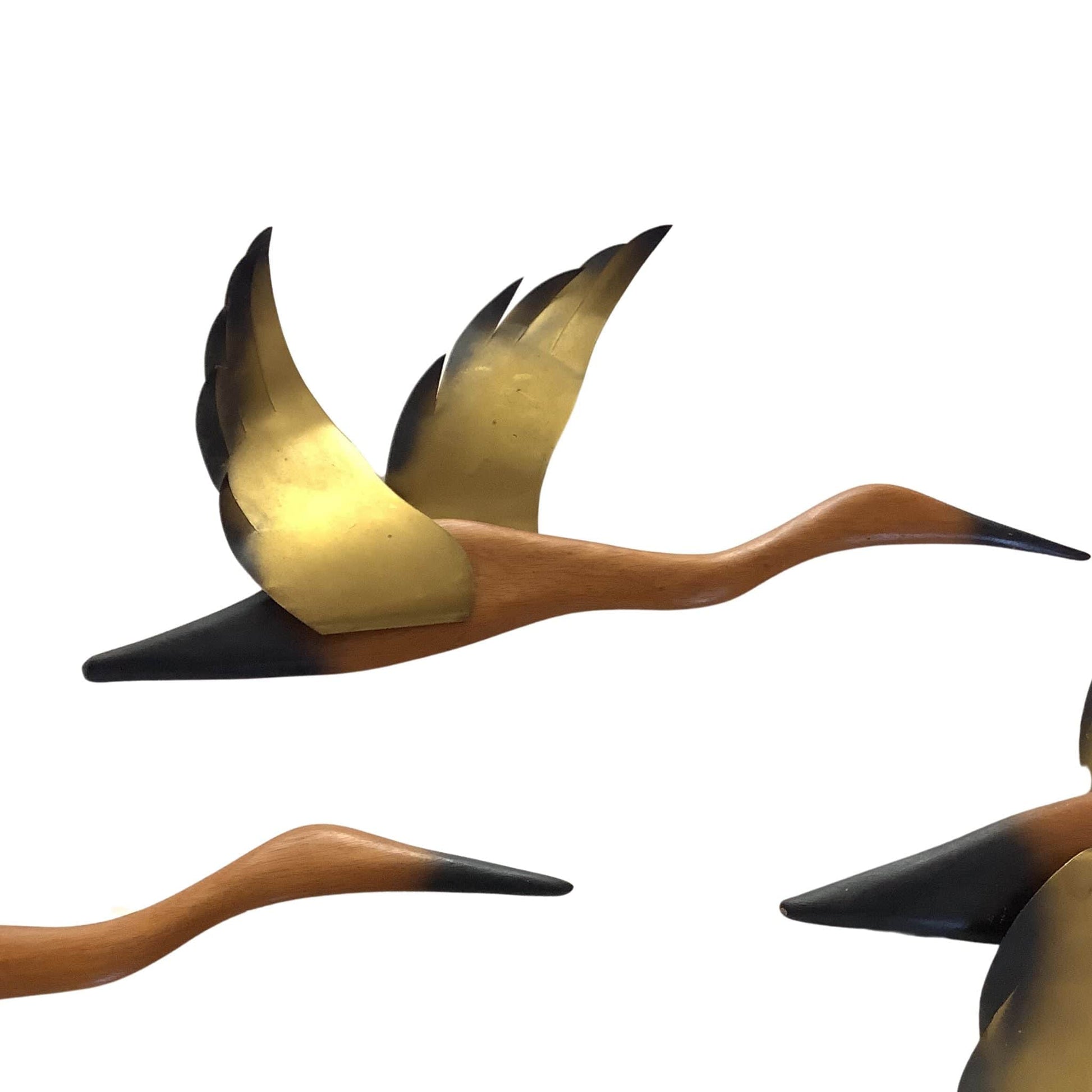 View of brass wings of  bird sculptures on a white background