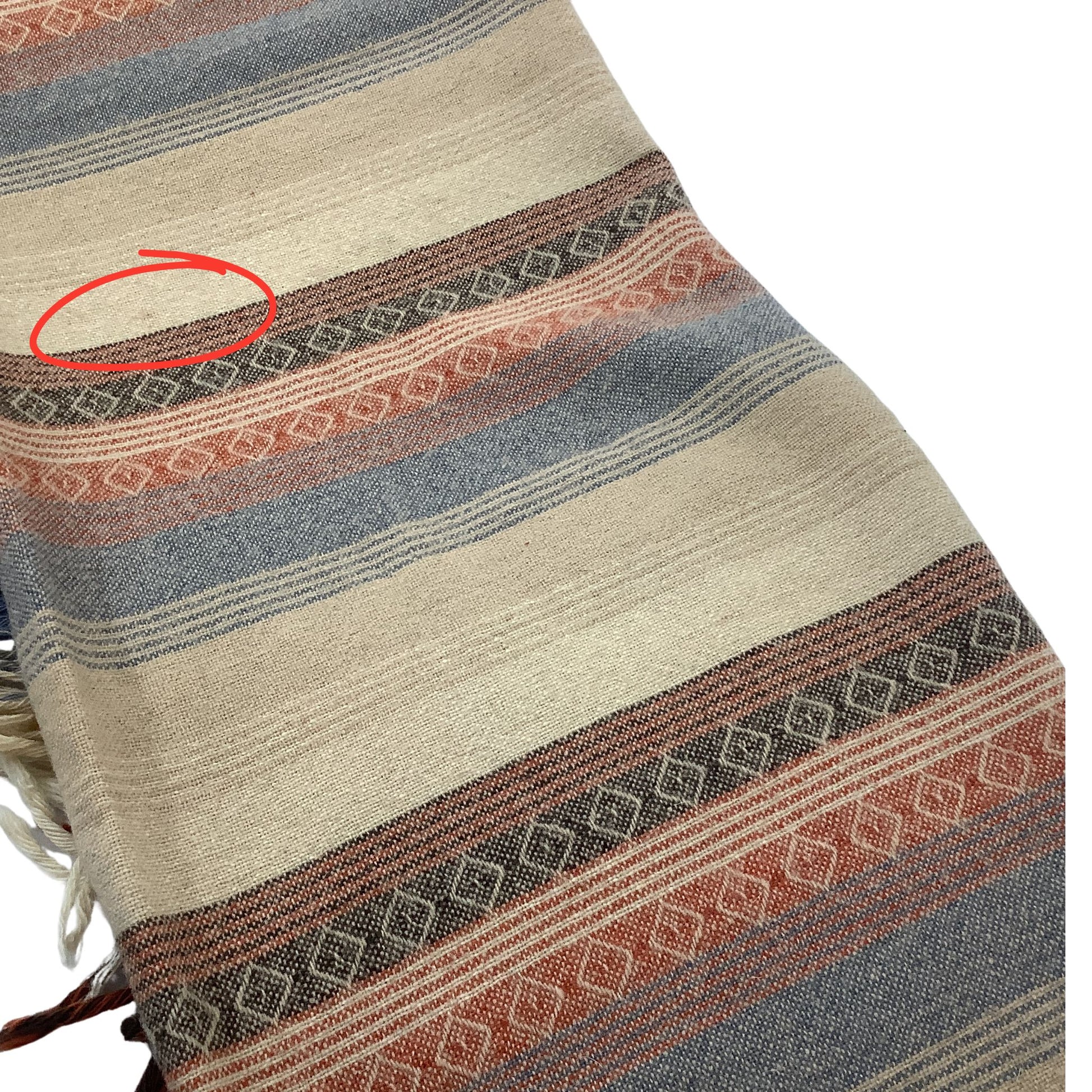 A close-up of a woven textile with horizontal stripes in beige, blue-gray, rust orange, and dark brown, featuring a red circle highlighting a section of the weave.