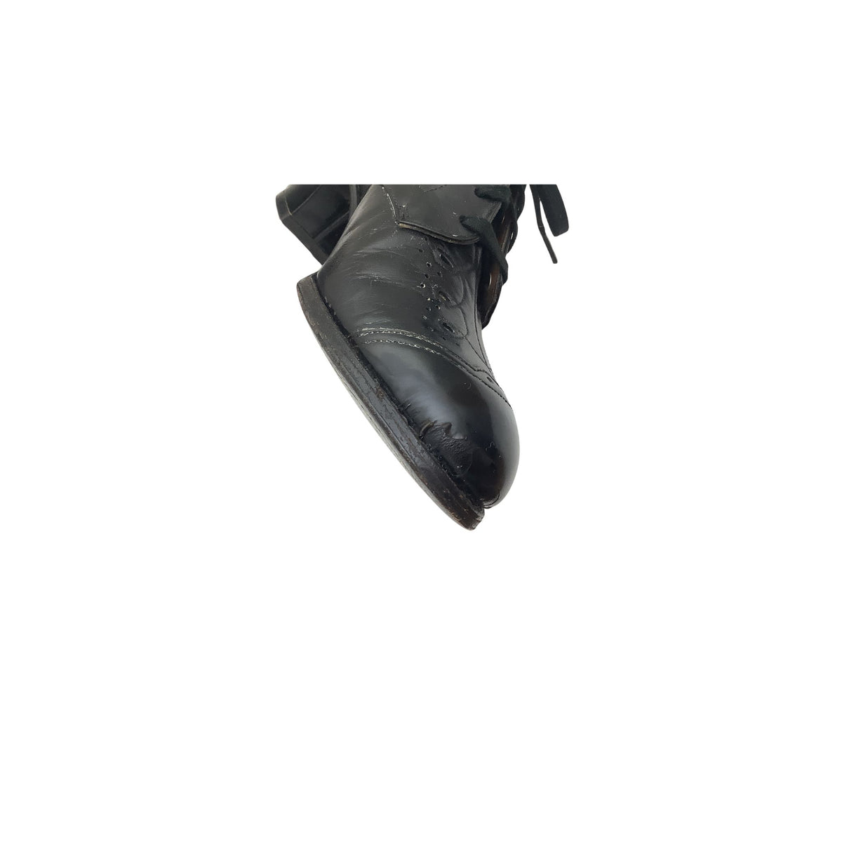 A close-up of a black leather vintage shoe shown from the side with visible peeling against a plain white background.