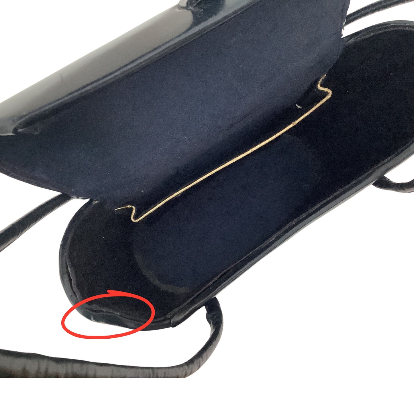  interior view of a vintage handbag, showing a gold metal trimmed interior pocket and a red circled area of a small tear on the top left corner of the purse.