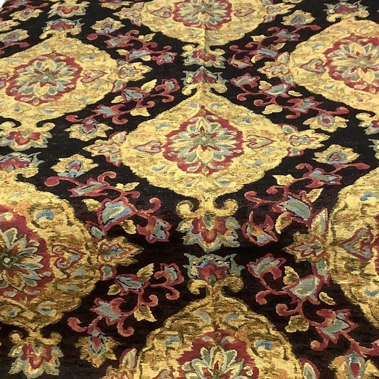 A close-up of a patterned fabric with a black background and large ornate medallions in gold, burgundy red, and muted blue-green.