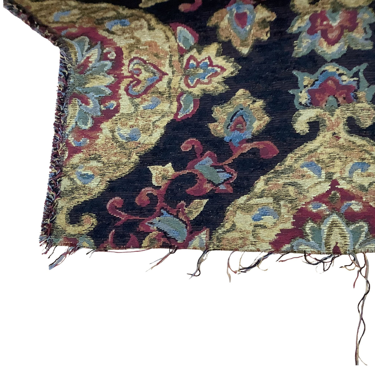 A close-up of a vintage baroque medallions patterned fabric showing a dark navy blue field with ornate floral motifs in beige, burgundy red, and light blue, finished with frayed edges.