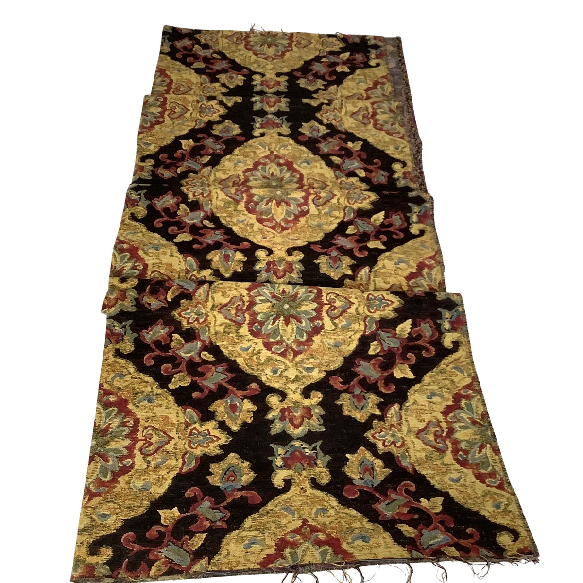 A vintage baroque medallions fabric folded showing  a black background, and featuring large gold, red, and green floral medallions and scrolling patterns.