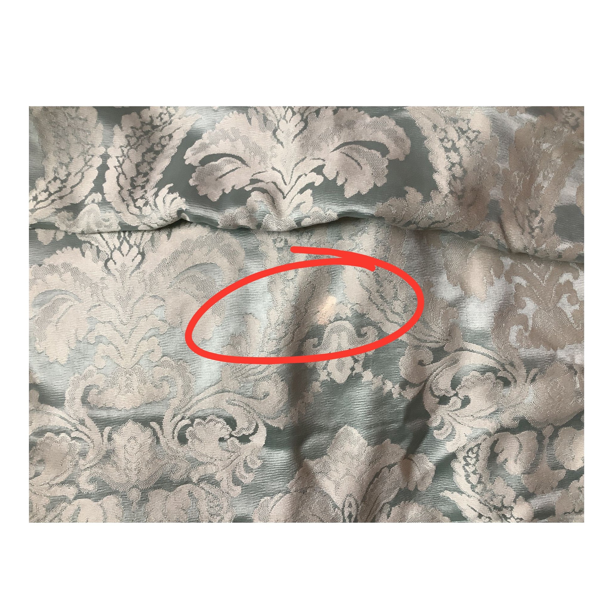 Vintage blue brocade fabric with red circle over discoloration