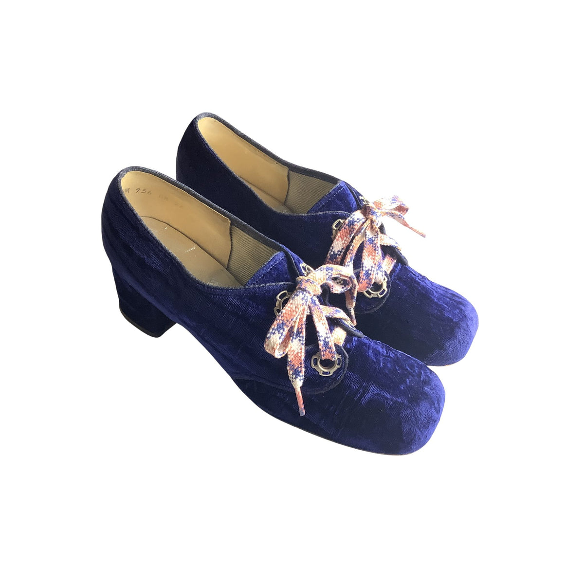 Pair of blue velvet shoes with decorative shoelaces on a white background