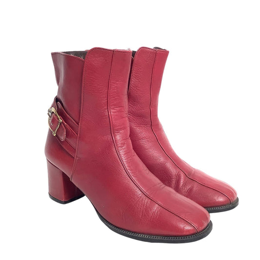 Pair of burgundy leather boots with a gold buckle on a white background