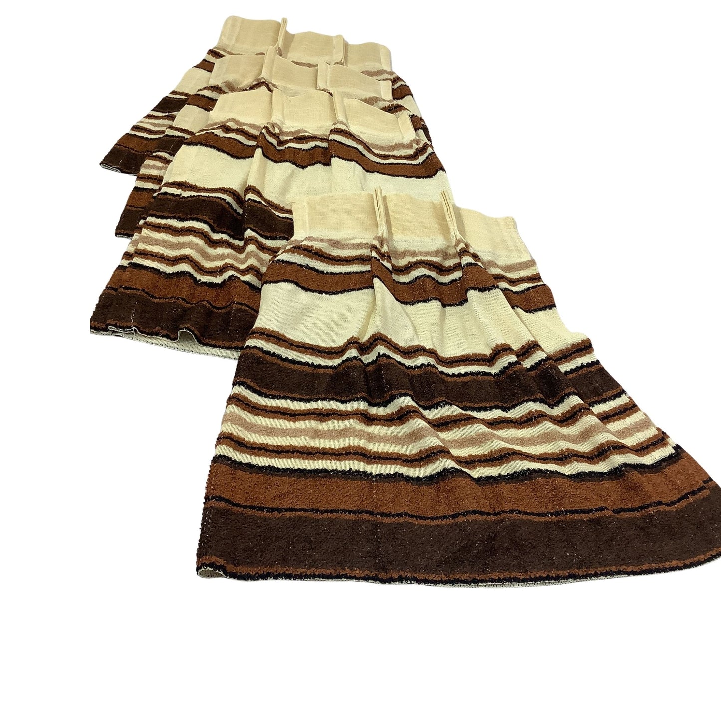 Top view of stacked curtains in striped knit in brown, beige, and black, arranged overlapping on a plain white background.