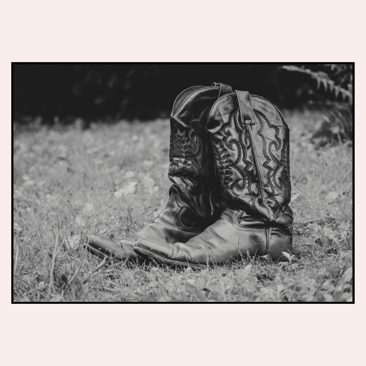Pair of cowboy boots on grass with a blurred background