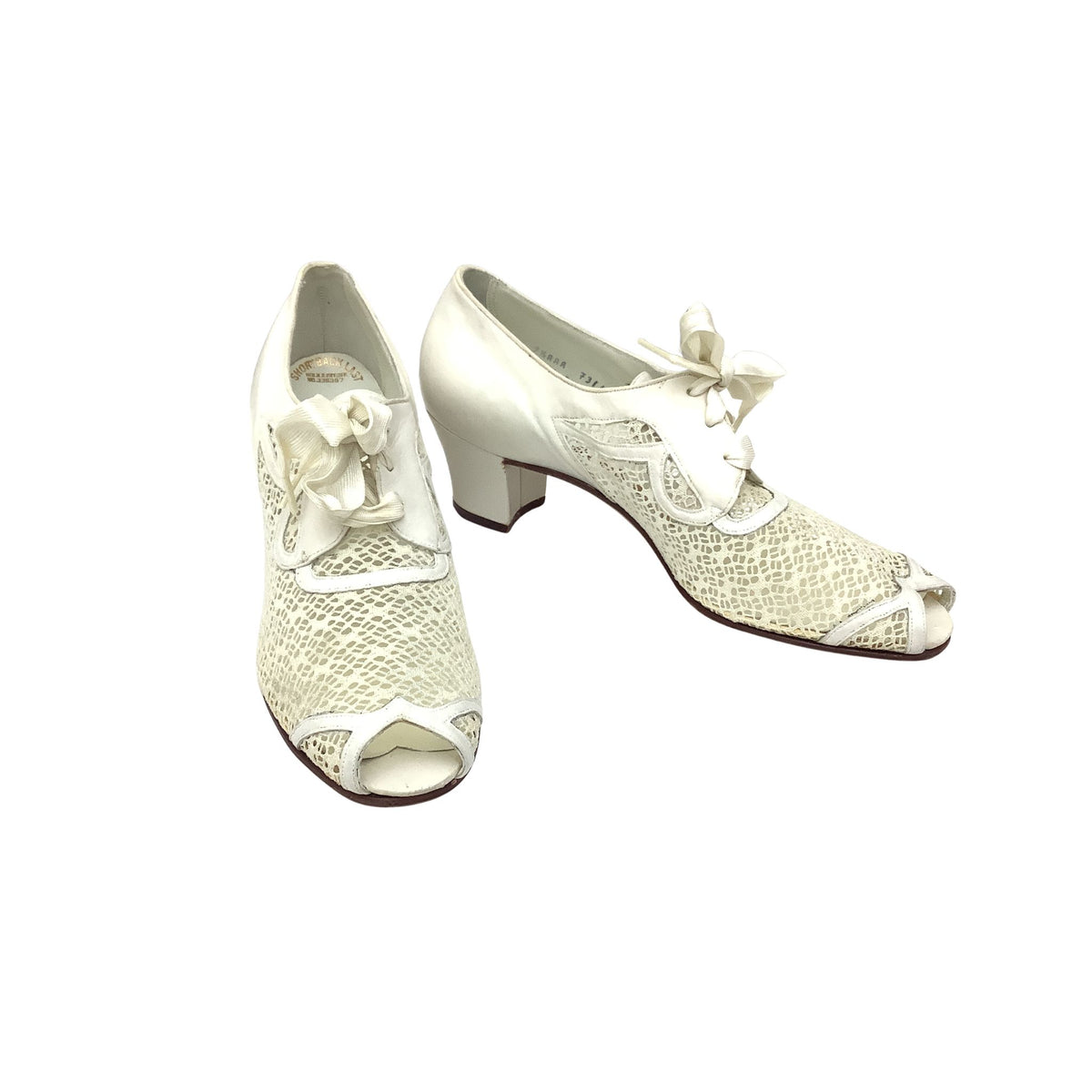 A pair of authentic vintage 1940s mid block-heel oxford shoes in white leather, featuring a textured mesh fabric, peep toe and side panels, laced up with bow details.