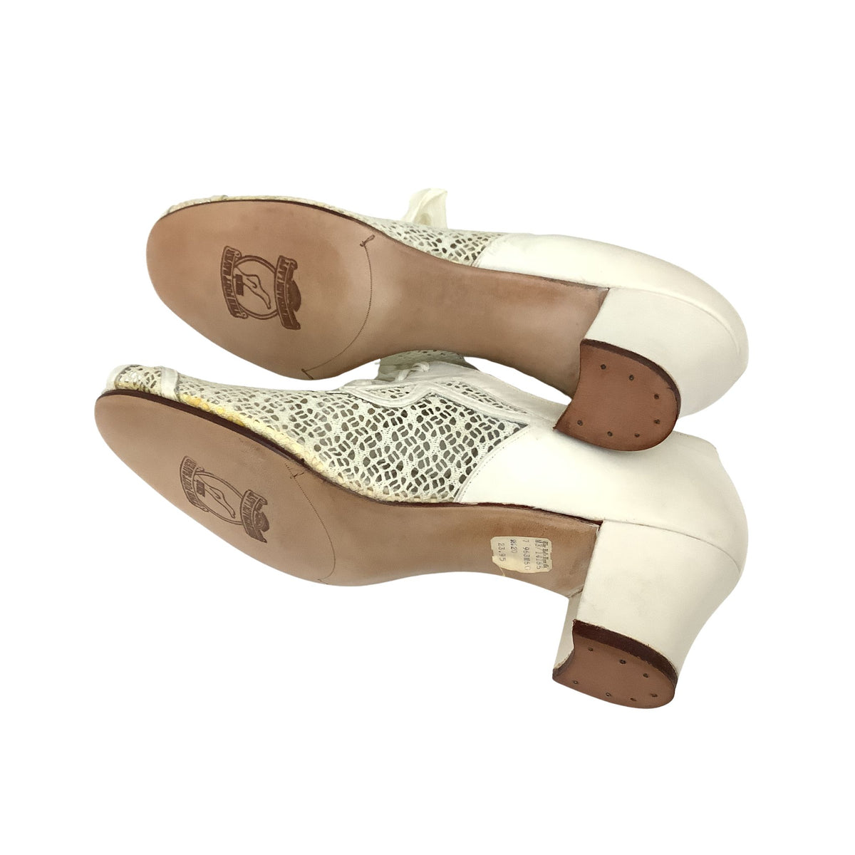 Sole view of a pair of authentic vintage 1940s mid block-heel oxford shoes in white leather, featuring a textured mesh fabric, peep toe and side panels, laced up with bow details.brown soles with a visible brand logo.