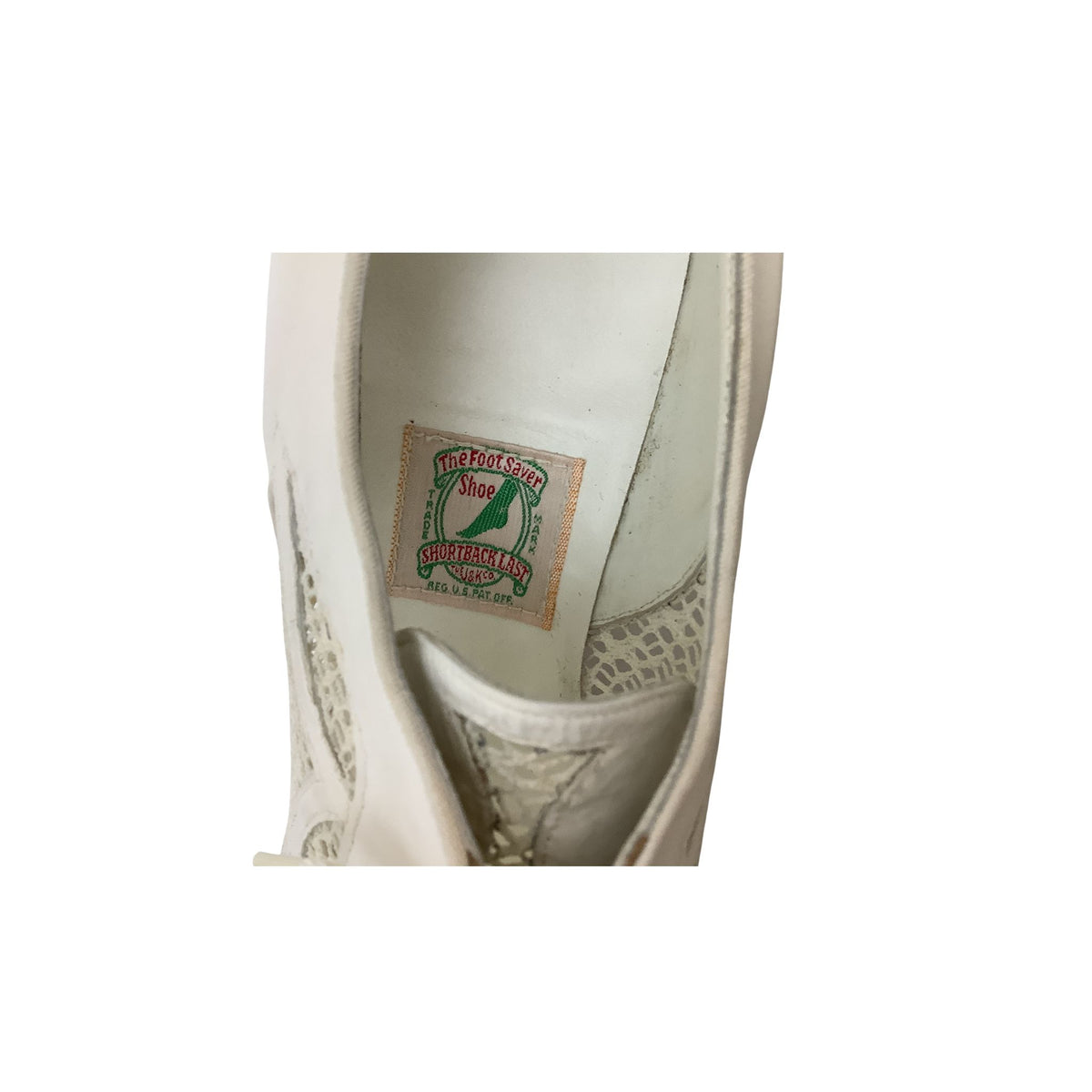 Close-up of the interior lining of a white shoe, showing authentic vintage brand label that reads 'THE FOOT SAVER SHOE SHORTBACK LAST'