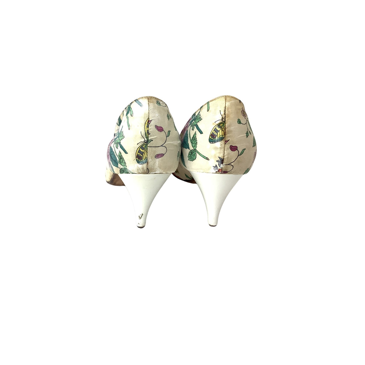 A pair of women's high-heeled shoes shown from the back, featuring a cream-colored satin fabric upper with a colorful butterfly and floral print, and solid white pointed stiletto heels.