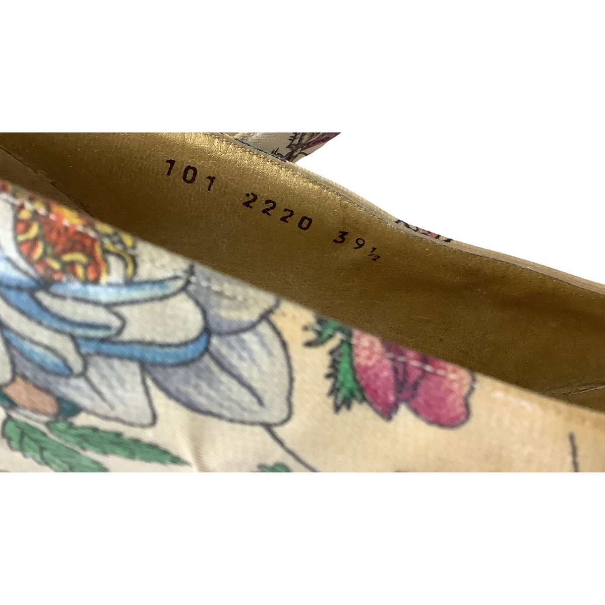 Close-up of the interior lining of a floral-patterned shoe, showing a tan suede-like surface printed with number markings and a multicolor floral design on a cream background.