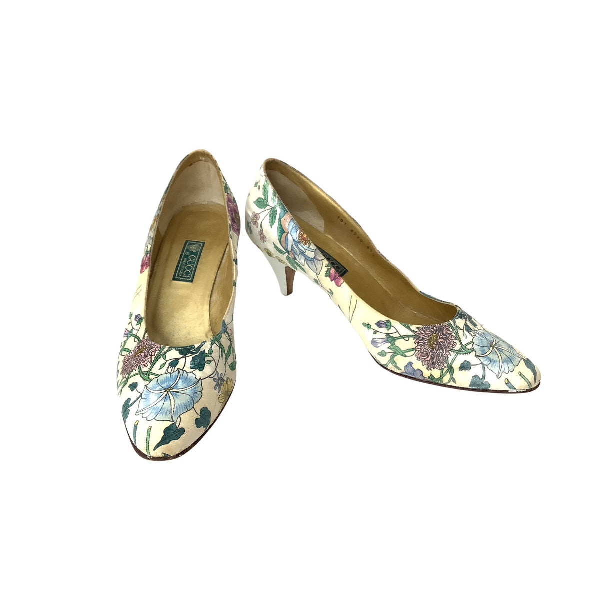 Vintage Gucci almond-toe mid-height pumps featuring a cream-colored fabric upper with a detailed floral pattern in blue, green, and purple, shown against a plain white background.