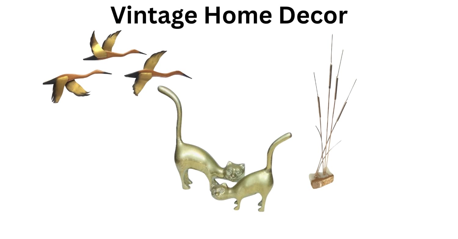 A collection of vintage home decor items on a plain white background, including a pair of gold-toned cat figurines, three flying bird decorations, and a brass reed on a marble base decor accent.