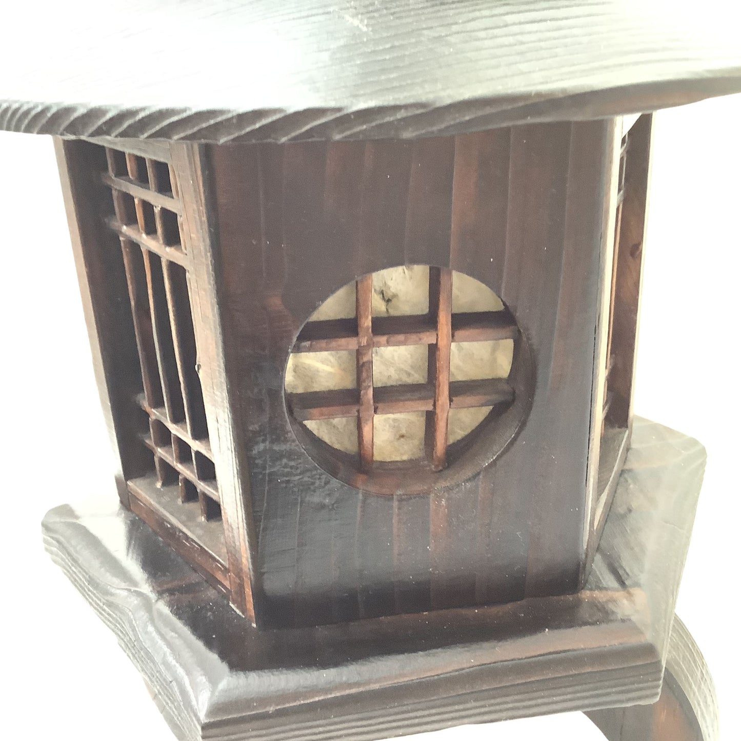 A close-up of a dark brown wooden decorative lantern or box with lattice window details and a circular cutout, with damage shown against a bright white background.