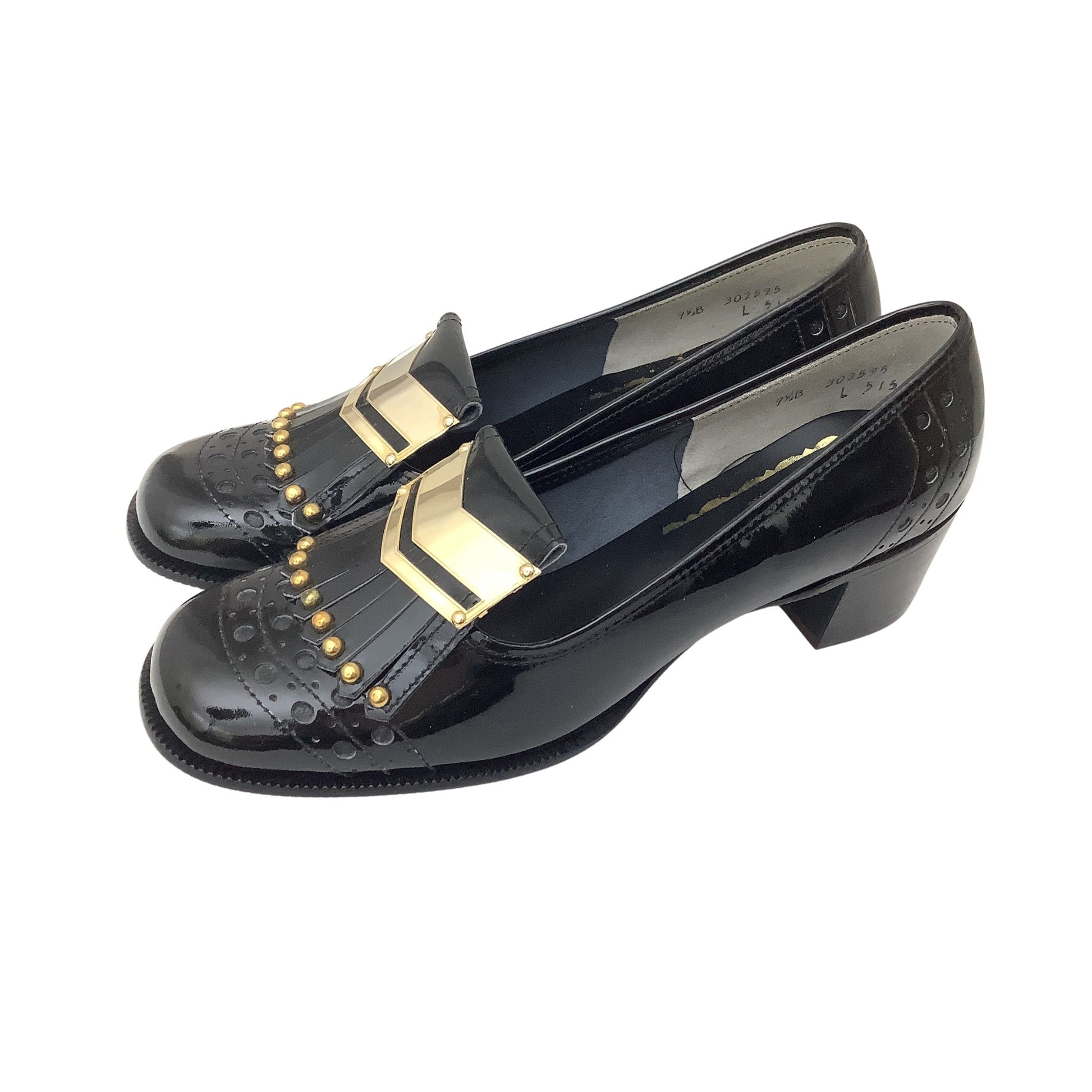 A pair of vintage black patent leather fringe loafers with gold chevron and stud embellishments, shown on a plain white background.