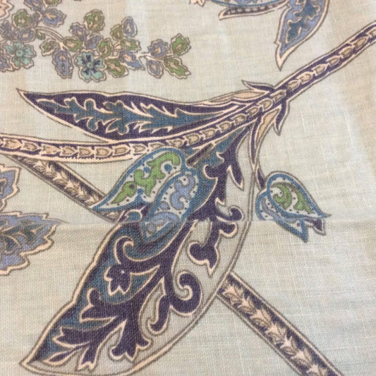 A close-up of a woven linen textile featuring an ornate paisley and floral pattern in navy blue, teal, and green.