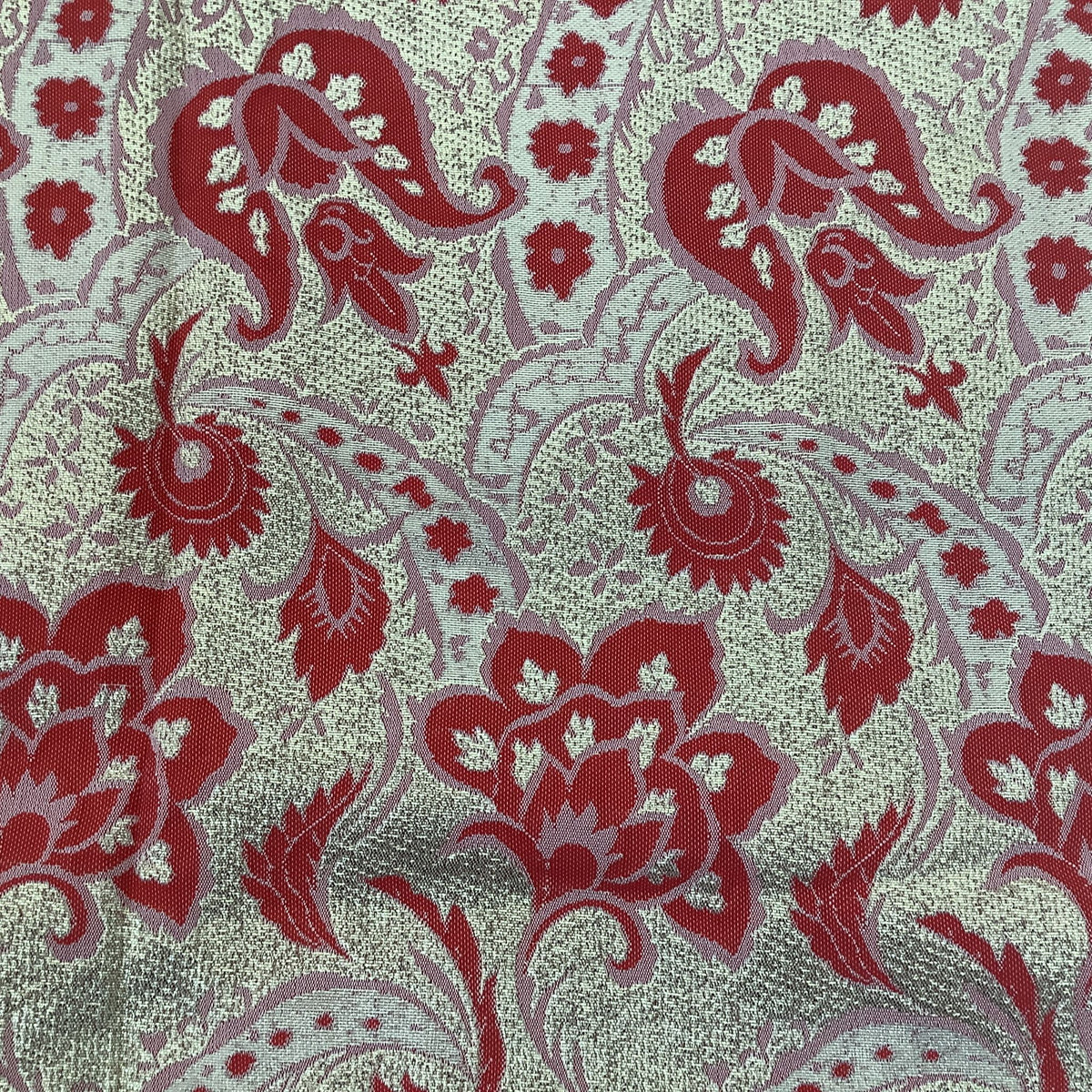 A close-up of a woven fabric with a red and gold floral pattern.