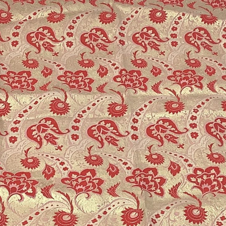 Close up of vintage gold and red brocade fabric with a woven floral pattern.