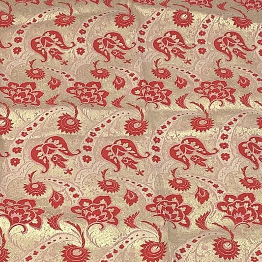 Close up of vintage gold and red brocade fabric with a woven floral pattern.