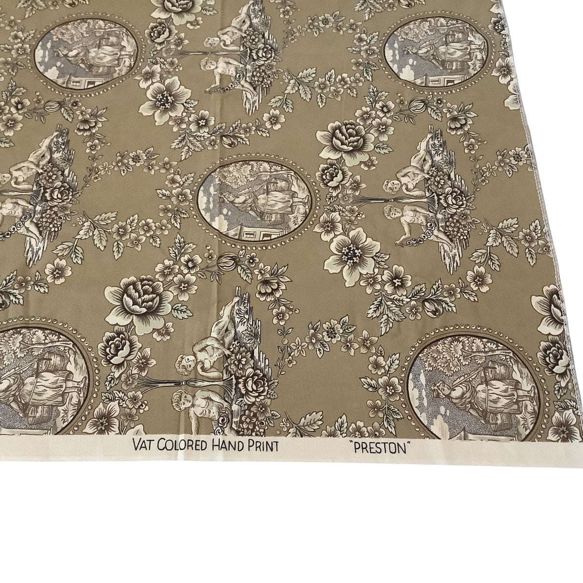 A close-up of a vintage-style fabric or wallpaper pattern labeled 'PRESTON' and 'VAT COLORED HAND PRINT.' The design shows a brown and beige background with repeating floral motifs, small figures, and oval scenic illustrations in muted gray-brown tones.