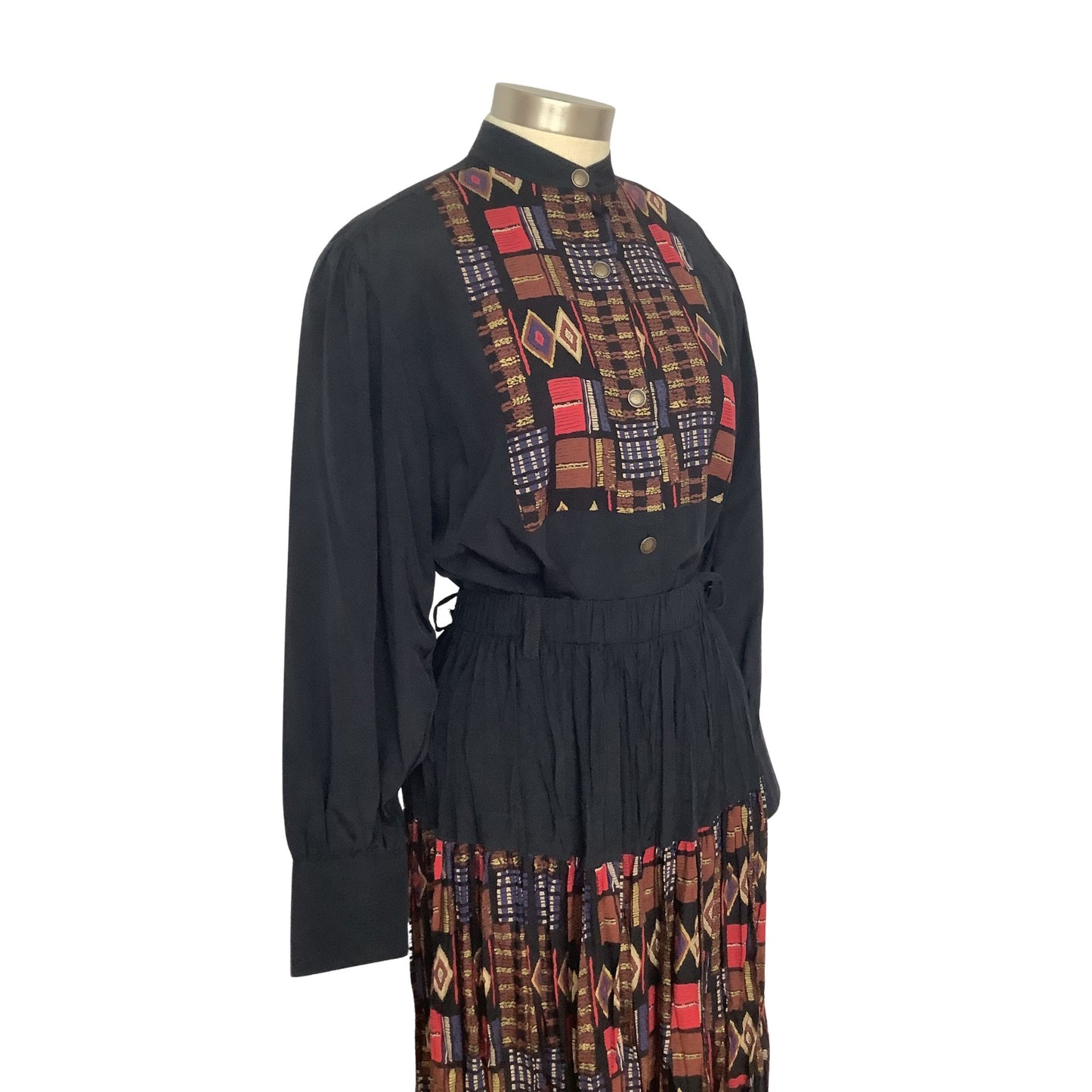 A long-sleeve Sherry Holt outfit view displayed on a mannequin featuring a geometric multicolor patterned yoke and a matching patterned skirt.
