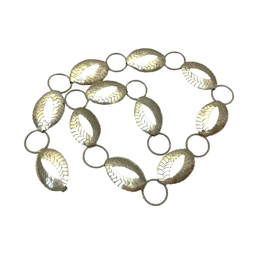 A vintage-style metallic link chain belt featuring elongated oval links with leaf-like textured patterns and circular connector rings, shown on a plain white background.