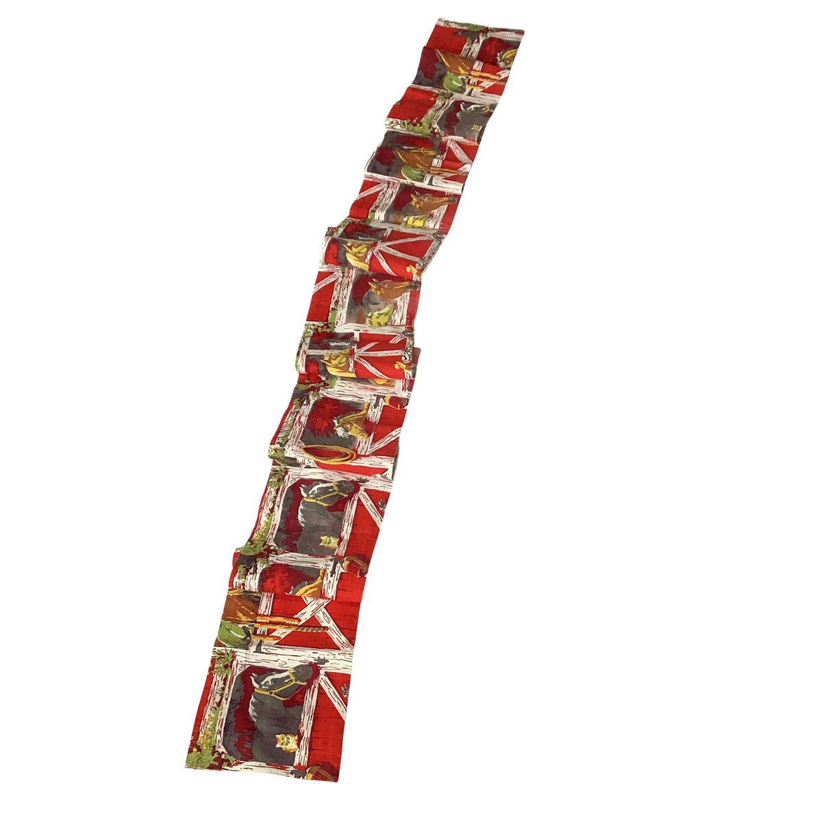 Vintage western curtain valance folded featuring a repeating pattern of horses and barn in red, gold and white colors.