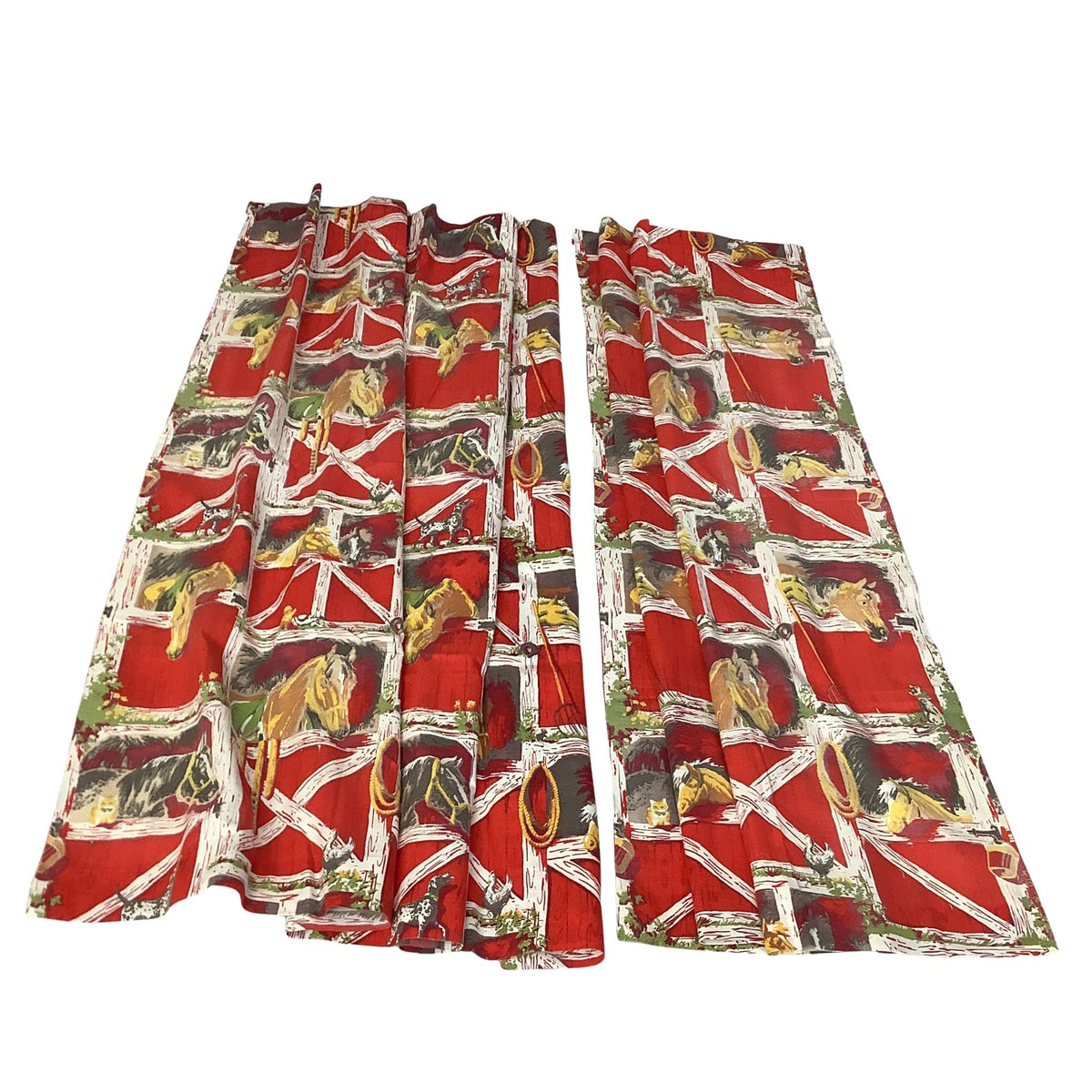 Overview of a pair long curtains in a western pattern featuring a red barn with white trim and painted horses in yellow, brown, and gray inside the barn stalls.